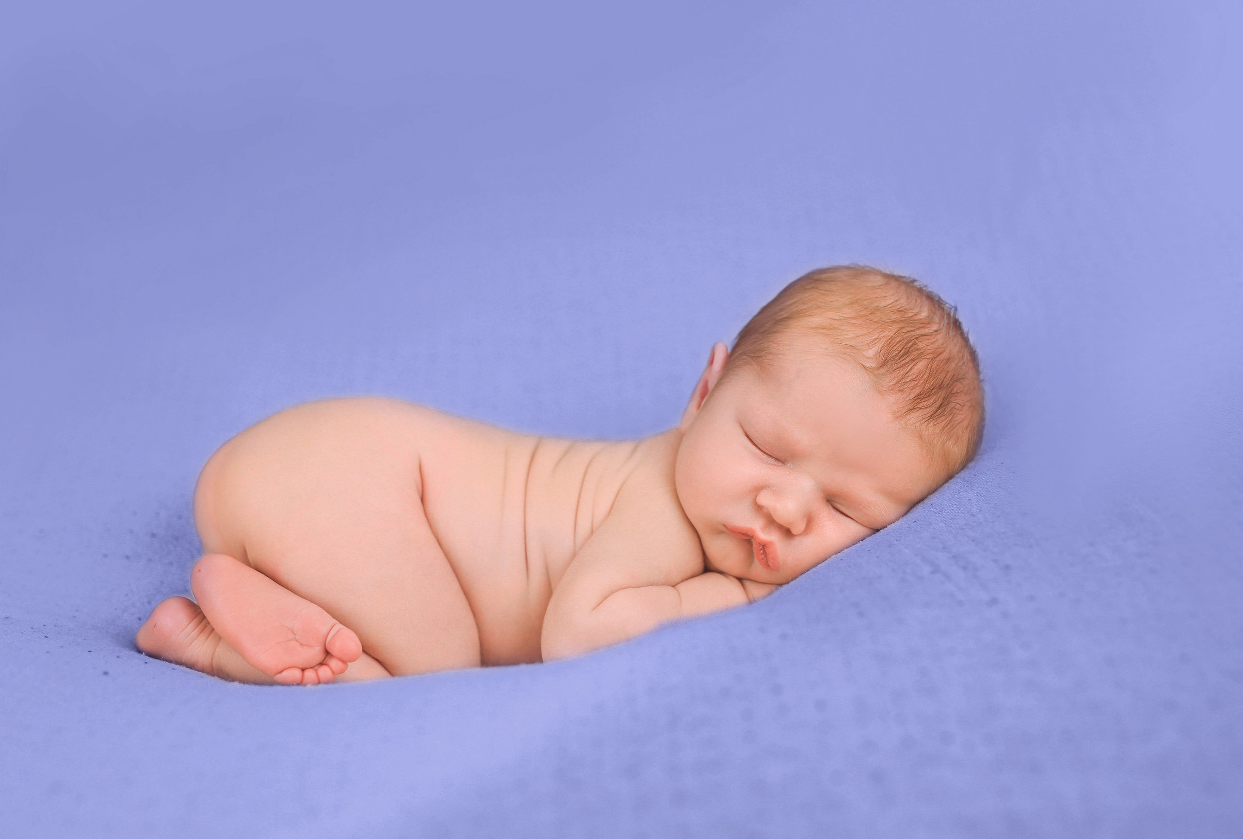 Newborn twins in name hats on a cobalt backdrop